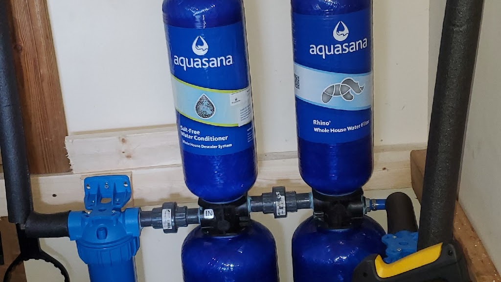 Bravo Plumbing Solutions — twin Aquasana salt-free conditioner and whole-house filter tanks plumbed on a utility-room stud wall