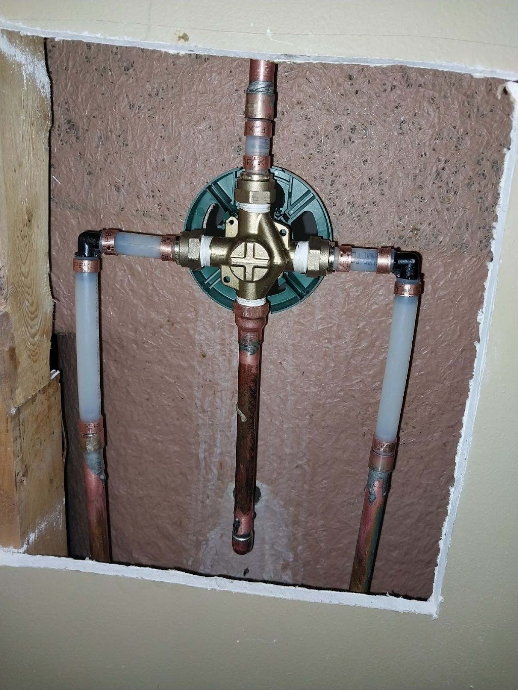 Bravo Plumbing Solutions — brass shower mixing valve rough-in with copper supply stubs through the drywall opening