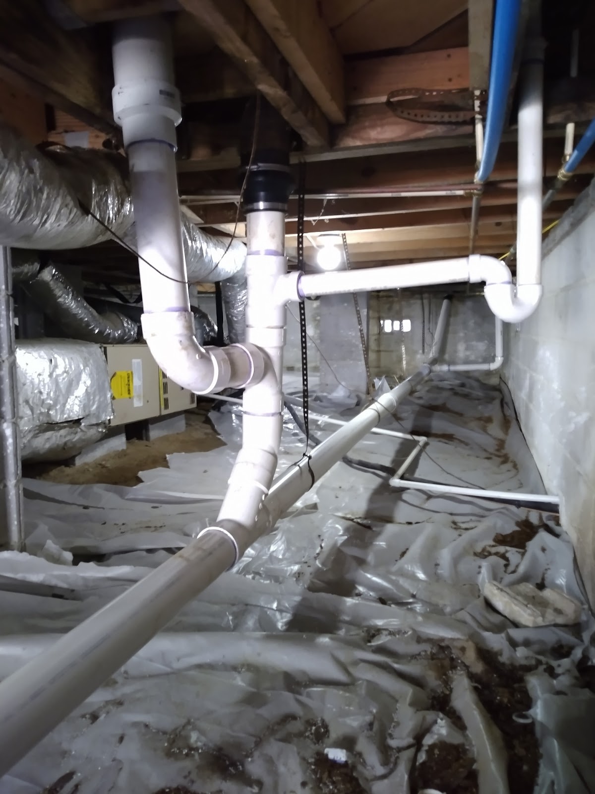 Bravo Plumbing Solutions — new PVC waste and vent tree installed under the first floor of a crawlspace home